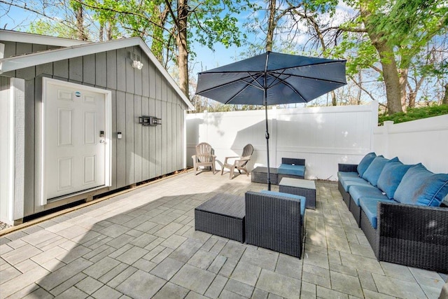 view of patio / terrace featuring an outdoor living space, a fenced backyard, and an outbuilding