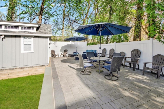 view of patio featuring a fenced backyard, an outbuilding, and outdoor dining space
