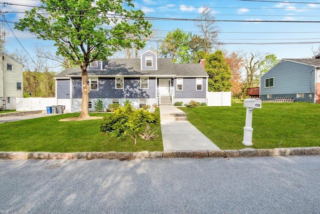 cape cod home with fence, a chimney, and a front yard