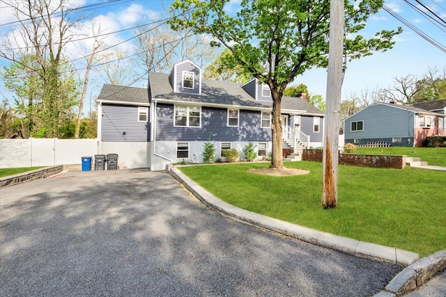 cape cod home featuring fence, aphalt driveway, and a front yard