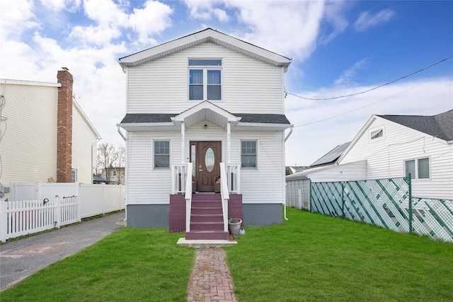 71 E Kissimee Rd, Lindenhurst, NY 11757 - view of front facade with roof with shingles, a front lawn, and fence