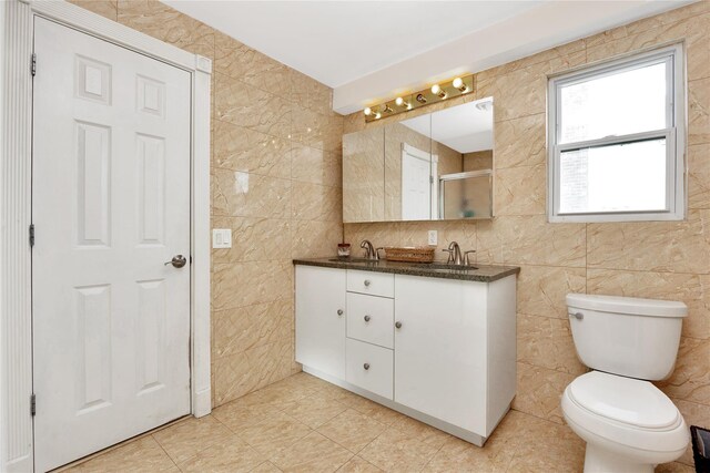 71 E Kissimee Rd, Lindenhurst, NY 11757 - bathroom with tile patterned floors, a shower with door, vanity, tile walls, and toilet