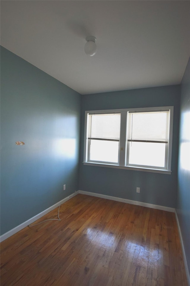 spare room featuring wood finished floors and baseboards