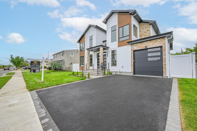 296 Division Ave, Hicksville, NY 11801 - contemporary home with stone siding, driveway, a residential view, and an attached garage