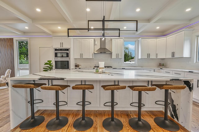 296 Division Ave, Hicksville, NY 11801 - kitchen with wall chimney exhaust hood, light wood-type flooring, coffered ceiling, healthy amount of natural light, and stainless steel double oven