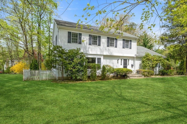 colonial house featuring fence and a front lawn
