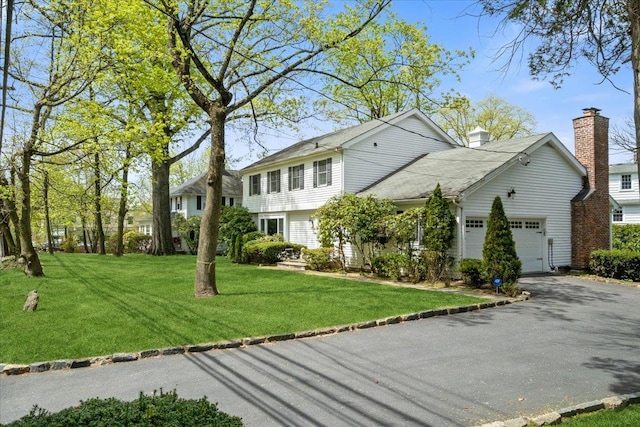 view of front facade with a garage, a front yard, and aphalt driveway