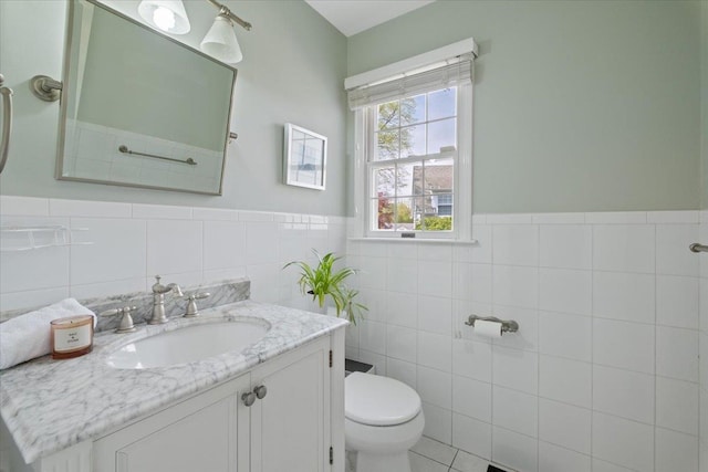 bathroom featuring tile walls, a wainscoted wall, vanity, and toilet
