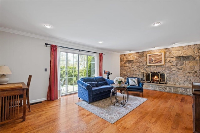 living room with visible vents, a fireplace, wood finished floors, baseboards, and ornamental molding