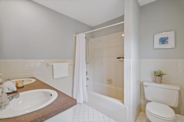 bathroom with shower / bath combination with curtain, toilet, tile walls, a wainscoted wall, and a sink