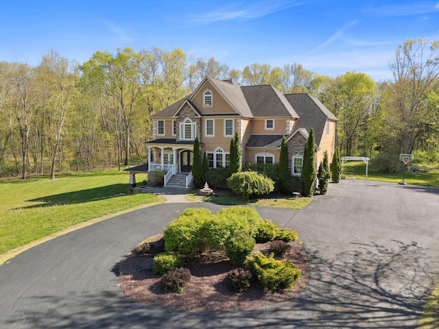 view of front of property featuring a porch, driveway, a front yard, and stucco siding