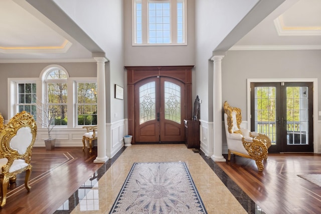 foyer entrance featuring french doors, decorative columns, and a wealth of natural light
