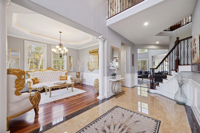 foyer entrance featuring wainscoting, a decorative wall, decorative columns, and a wealth of natural light