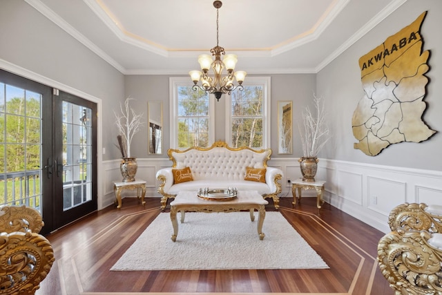 sitting room featuring french doors, wainscoting, dark wood finished floors, a chandelier, and a tray ceiling