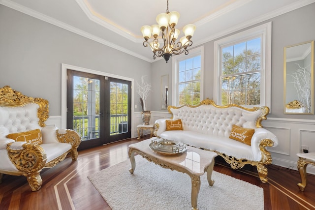 sitting room with crown molding, a notable chandelier, french doors, and a decorative wall