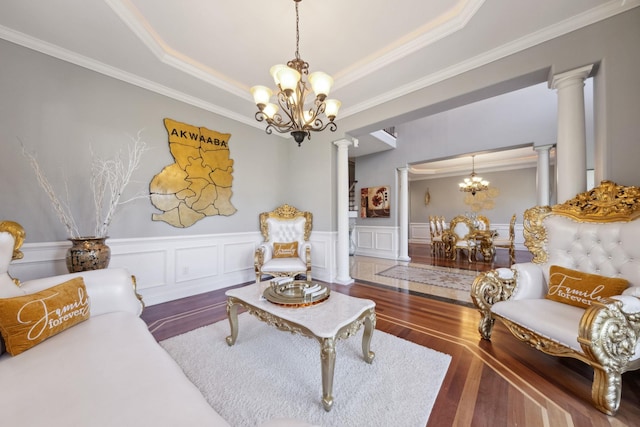 living room with crown molding, a notable chandelier, wainscoting, ornate columns, and hardwood / wood-style flooring