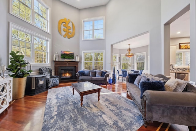 living room with a high ceiling, a glass covered fireplace, wood finished floors, and a wealth of natural light
