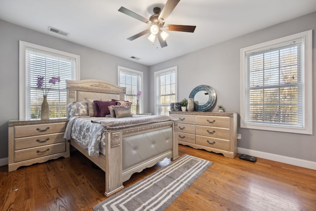 bedroom featuring visible vents, a ceiling fan, baseboards, and wood finished floors