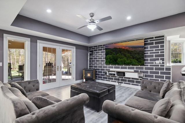 cinema room with a ceiling fan, a wealth of natural light, french doors, and wood finished floors