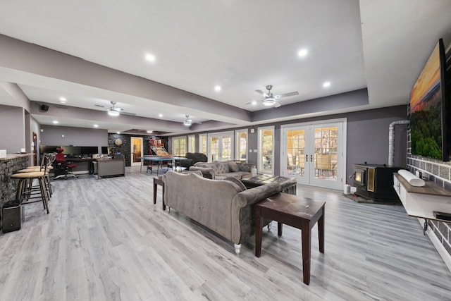 living room featuring a wood stove, light wood finished floors, and a ceiling fan