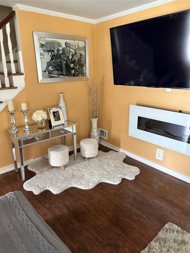 living area with visible vents, baseboards, wood finished floors, stairs, and ornamental molding