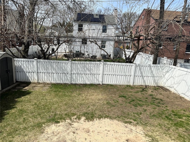 view of yard featuring a storage shed, a fenced backyard, and an outdoor structure