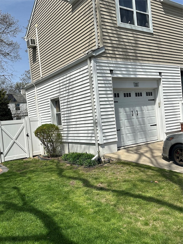 view of home's exterior featuring a gate, an attached garage, fence, and a lawn