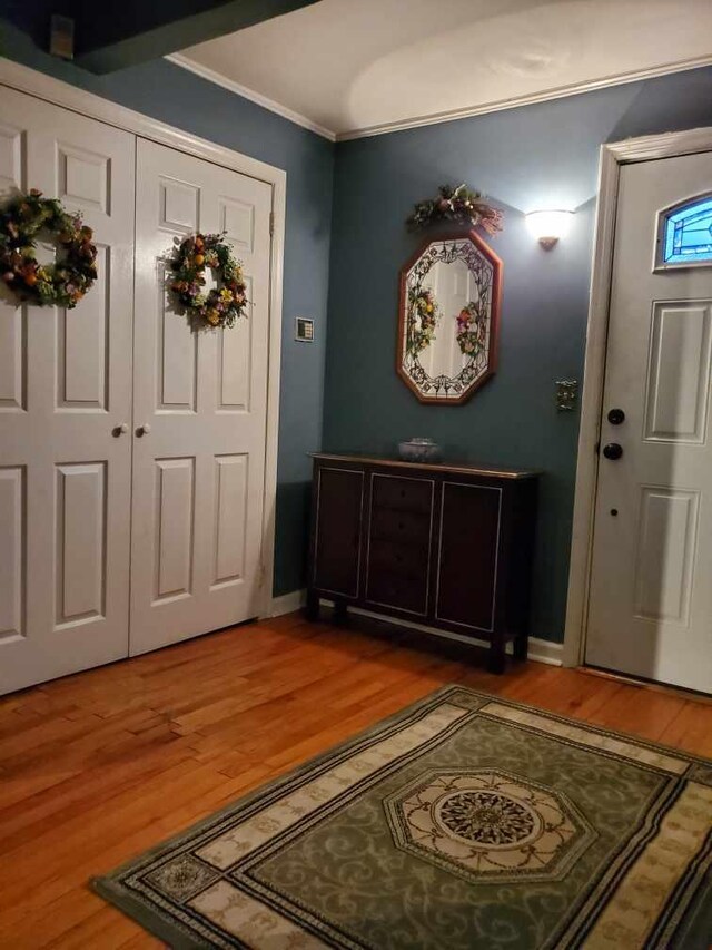 entryway with crown molding, baseboards, and light wood-type flooring