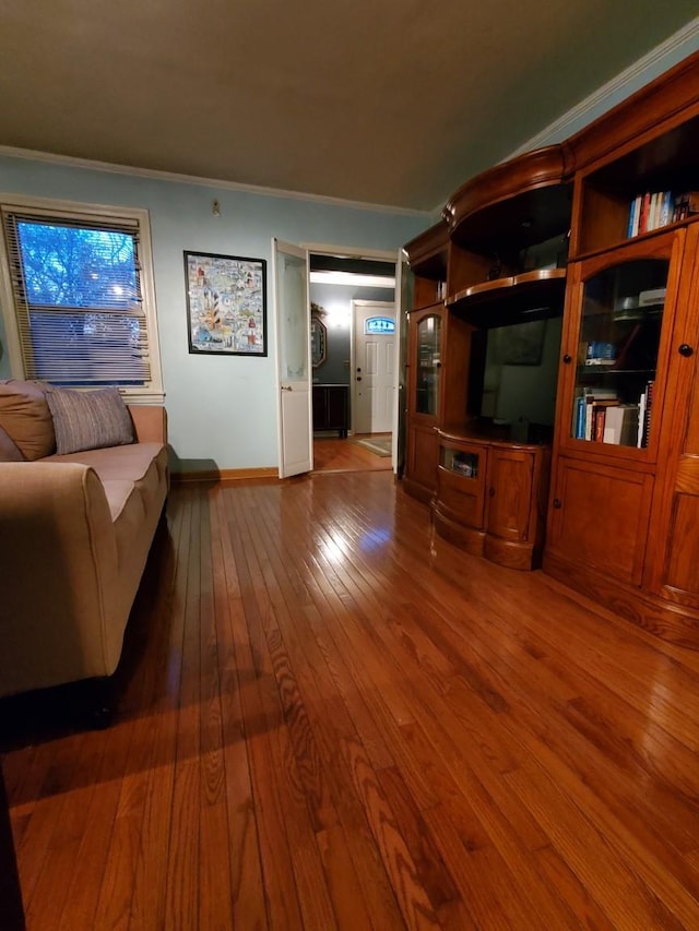 living area featuring baseboards, crown molding, and hardwood / wood-style flooring