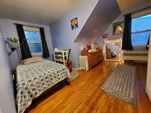 bedroom with radiator, lofted ceiling, and hardwood / wood-style flooring