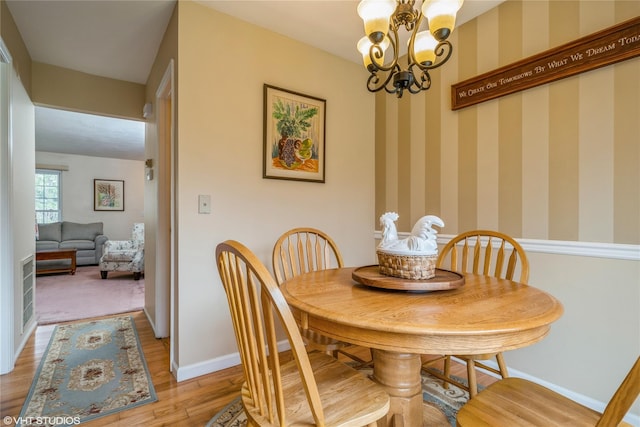 dining space featuring wallpapered walls, light wood-style flooring, baseboards, and an inviting chandelier