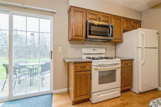kitchen featuring brown cabinets, light wood finished floors, and white appliances