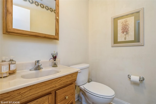 bathroom featuring baseboards, vanity, and toilet