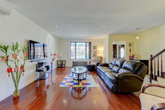 67-54 Groton St, Forest Hills, NY 11375 - living room with radiator, baseboards, a wall mounted air conditioner, wood finished floors, and stairs
