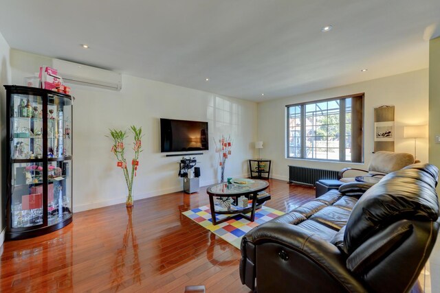 67-54 Groton St, Forest Hills, NY 11375 - living room with radiator, baseboards, recessed lighting, wood finished floors, and a wall mounted AC