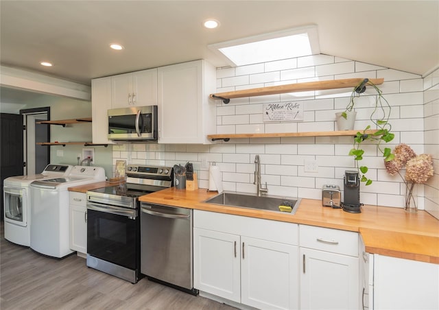 kitchen featuring open shelves, stainless steel appliances, a sink, and washing machine and clothes dryer