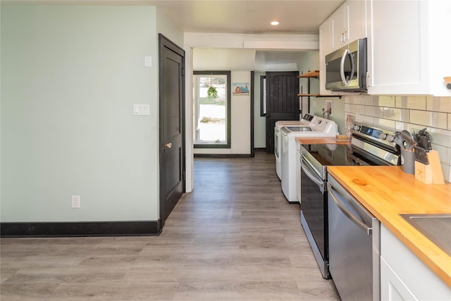 kitchen featuring white cabinets, stainless steel appliances, washer and clothes dryer, decorative backsplash, and wood counters