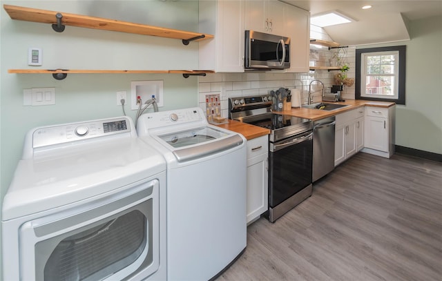 kitchen featuring open shelves, a sink, white cabinetry, appliances with stainless steel finishes, and independent washer and dryer