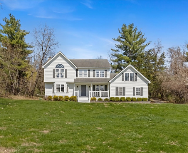 traditional home with a shingled roof, a front lawn, and covered porch