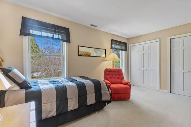 carpeted bedroom with multiple closets and visible vents