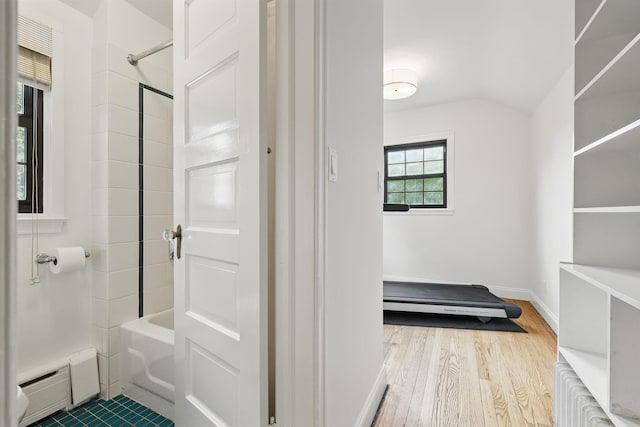 bathroom with a baseboard radiator, wood finished floors, baseboards, and tub / shower combination