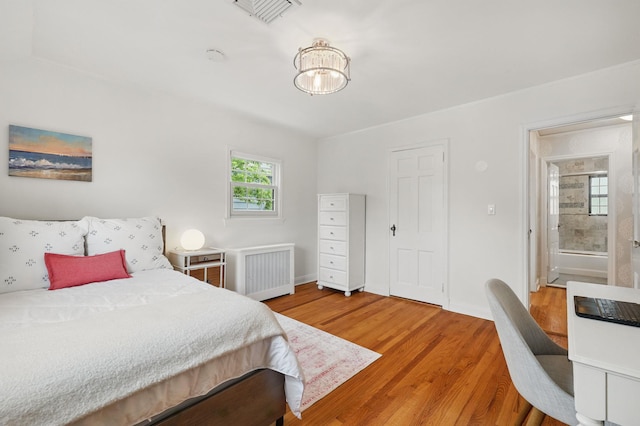 bedroom with radiator, light wood finished floors, baseboards, and a desk