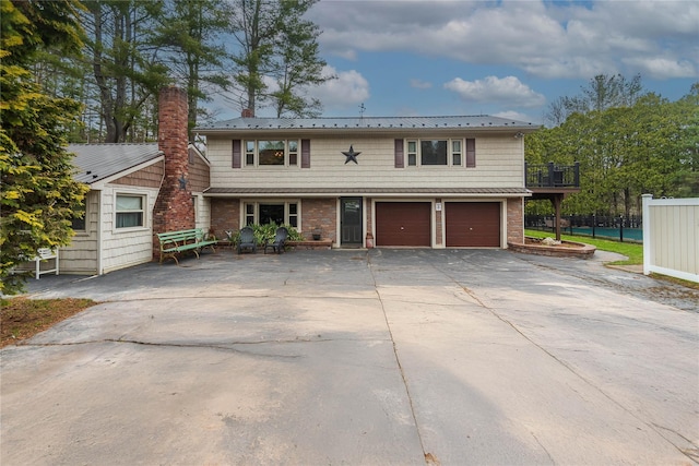 view of front of property with driveway, a chimney, metal roof, fence, and an attached garage