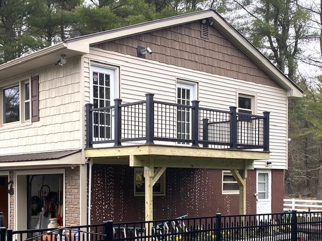 back of house with a wooden deck and stone siding