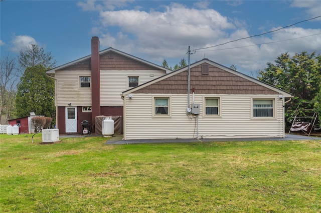 rear view of house featuring a lawn and a chimney