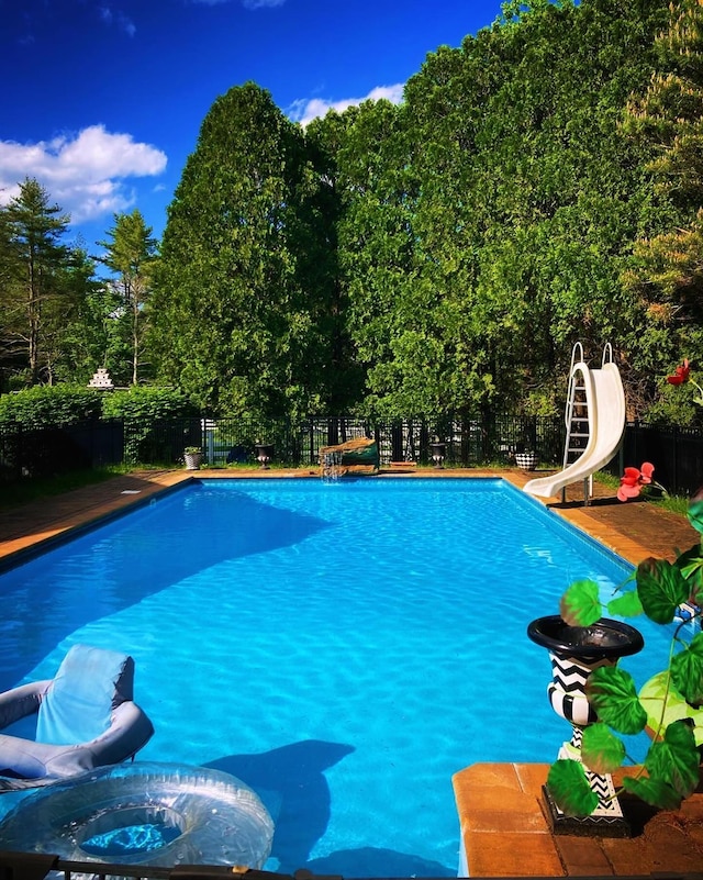 view of pool with a fenced backyard, a water slide, and a fenced in pool