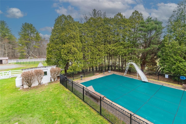 view of swimming pool featuring a fenced in pool, a water slide, fence, and a lawn