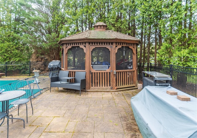 view of patio with fence, a fenced in pool, and a gazebo