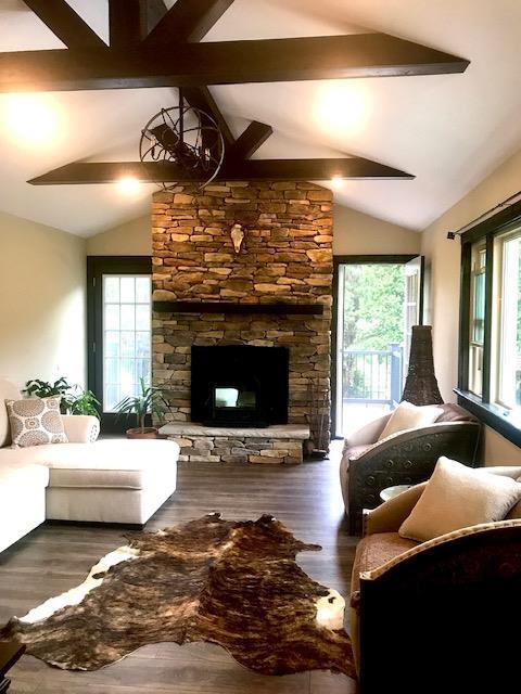 living area with plenty of natural light, wood finished floors, and lofted ceiling with beams