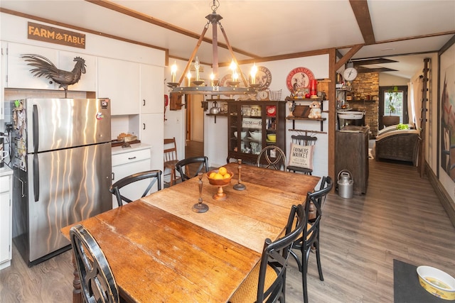dining space featuring a chandelier, wood finished floors, and vaulted ceiling with beams
